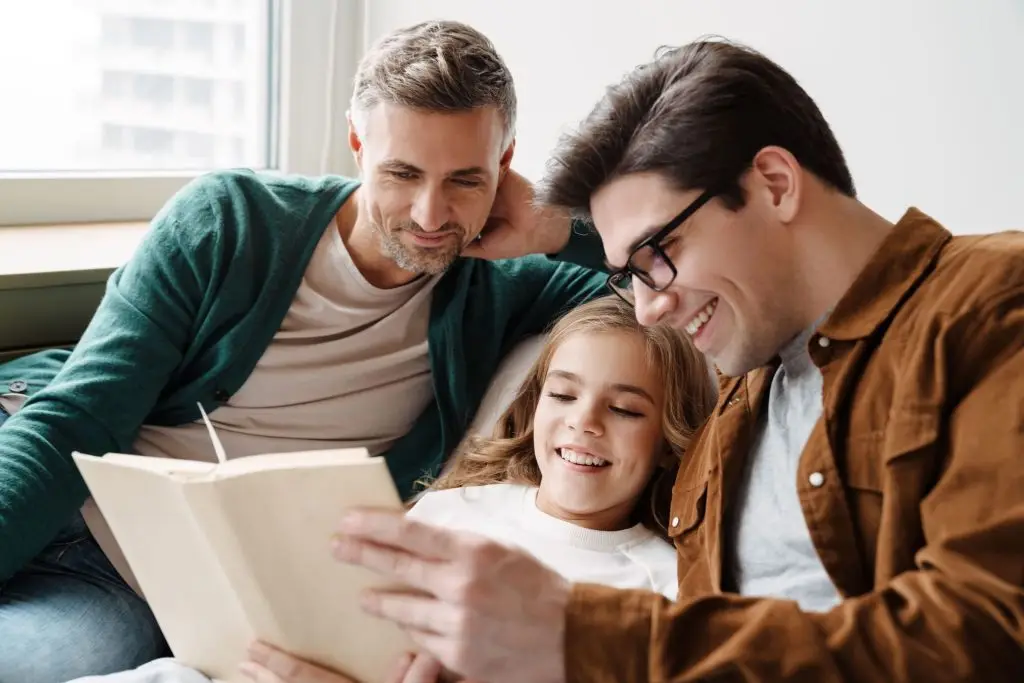 happy sam sex couple reading to their daughter